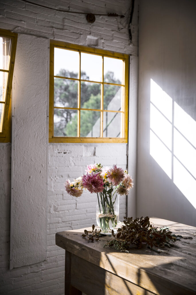 Wooden table with kitchenware and bouquets of fresh blooms in vases with water near white wall with replacement windows summerville sc